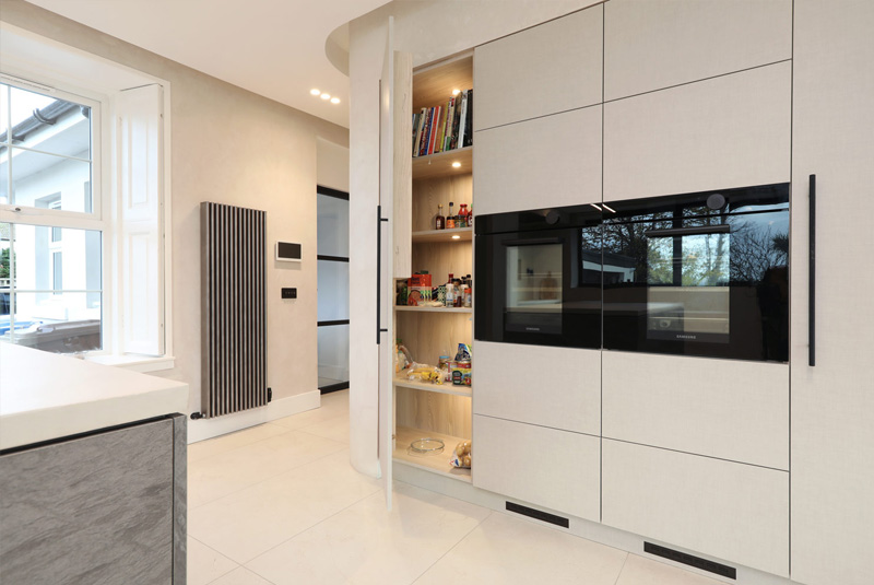Curved storage area with sliding door and inside lighting next to integrated oven